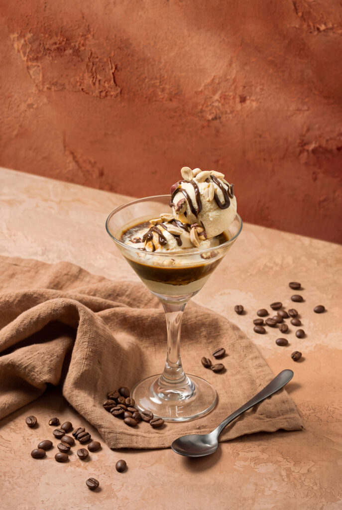 Copa de affogato martini con helado y chocolate junto a granos de café tostado esparcidos sobre tela de yute.