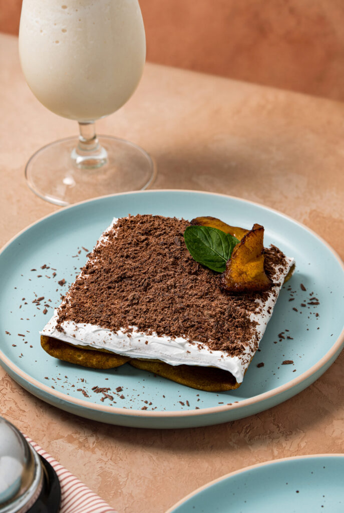 Crepa doblada cubierta de chocolate rallado y crema batida, con plátano y hojas de menta, junto a un smoothie de horchata con canela.